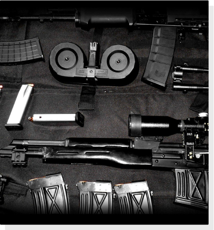 A collection of firearms, including a rifle and few magazines are neatly arranged on a black cloth in a Gun Ammo Shop
